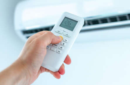 Air conditioner temperature adjustment with remote controller in room at home.